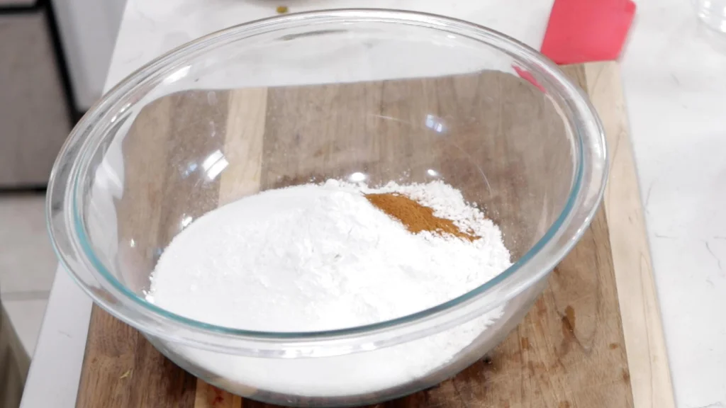 Flour and other dry ingredients in a bowl on a wooden cutting board.