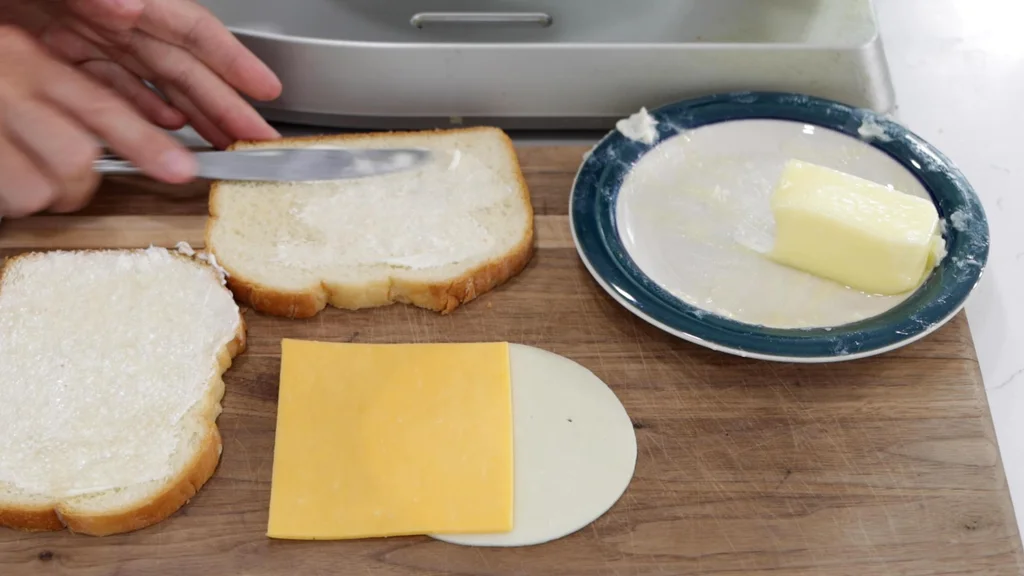 Hand buttering two slices of bread.