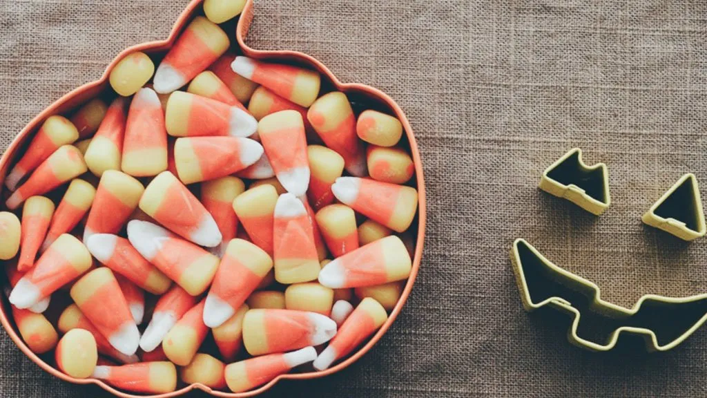 Candy corn in pumpkin dish on a table.