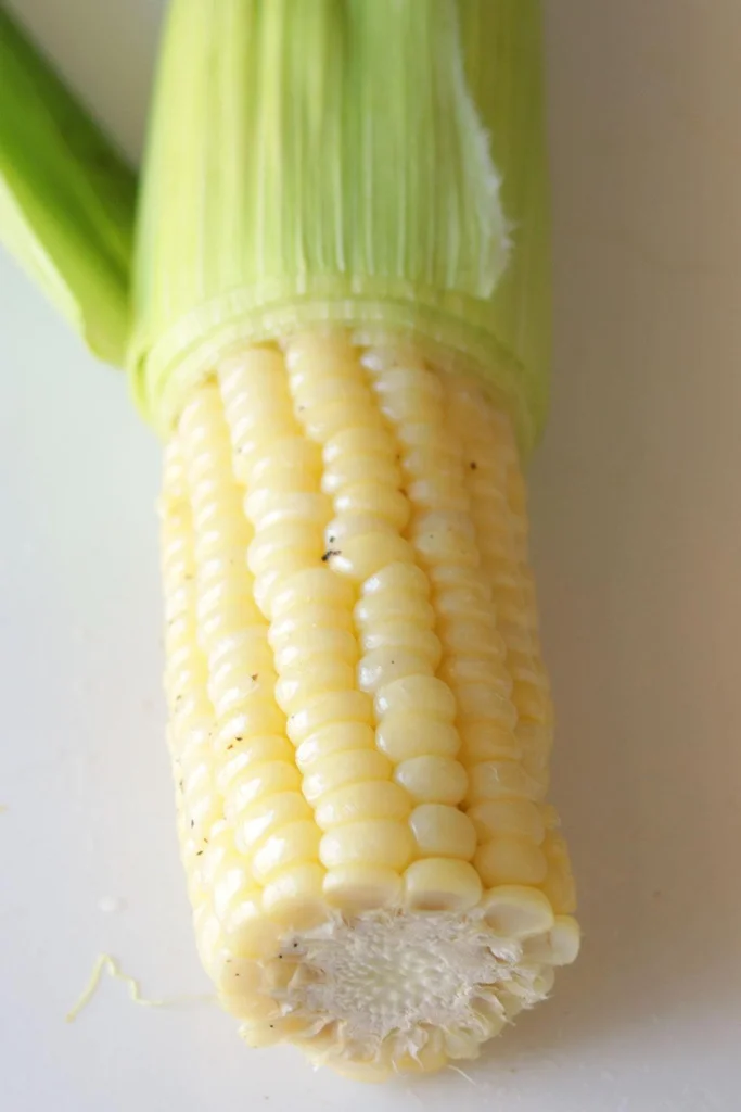Freshly cooked ear of corn on a white plate.