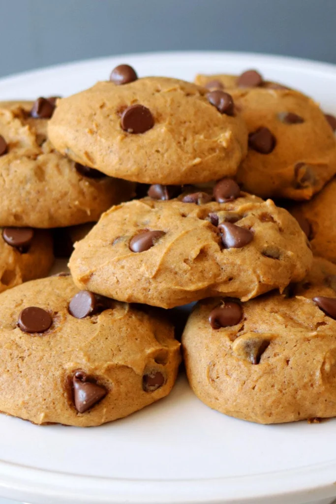 Fresh batch of homemade pumpkin chocolate chip cookies on a white plate. Fresh batch of homemade pumpkin chocolate chip cookies on a white plate.