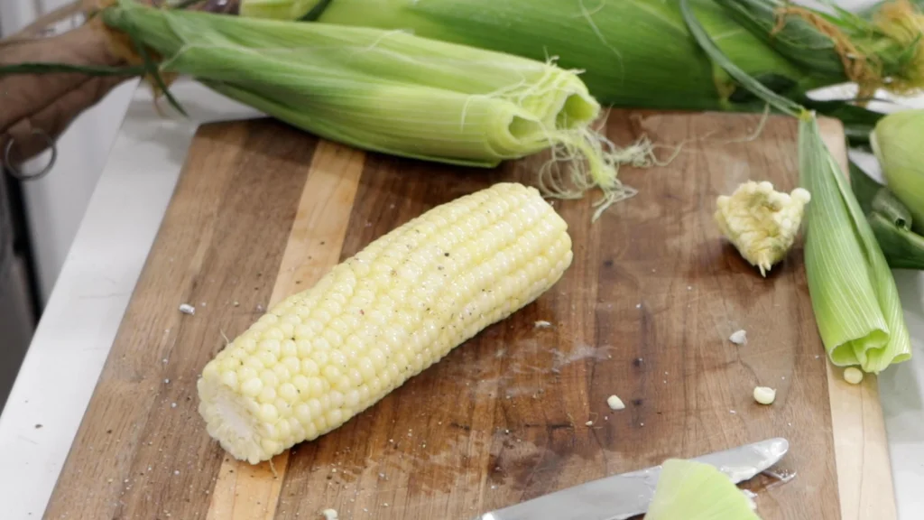 Seasoning microwaved corn on the cob with salt, pepper, and butter.