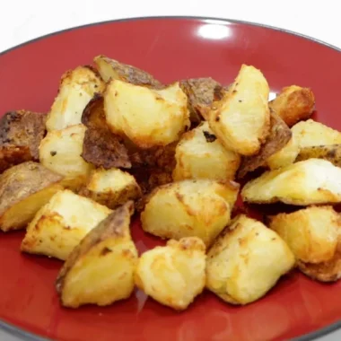Red plate with a mound of crispy air fryer potatoes on it.