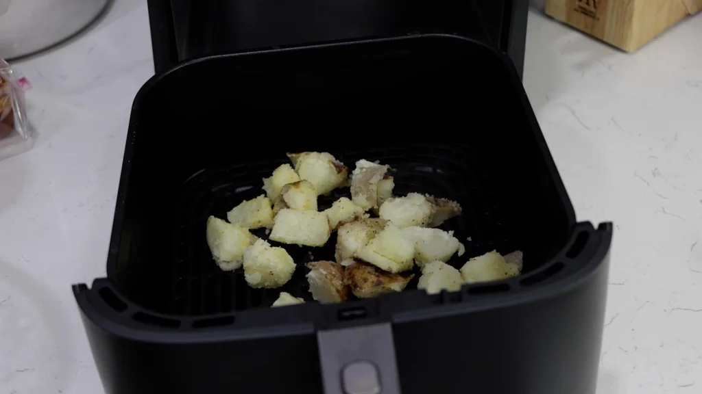 Seasoned potato chunks in an air fryer basket. Seasoned potato chunks in an air fryer basket.