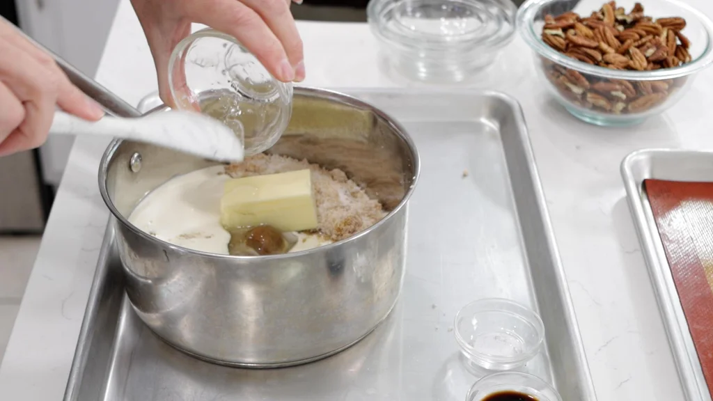 Hand scooping corn syrup into a bowl with sugar and butter. Hand scooping corn syrup into a bowl with sugar and butter.