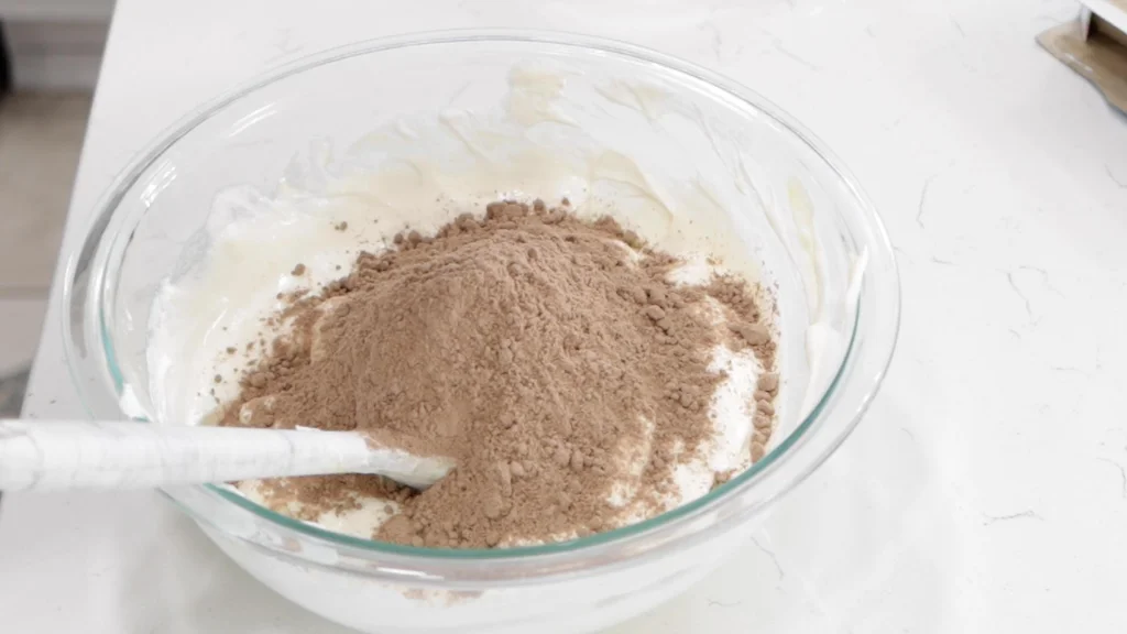 Pile of chocolate cake mix on top of the Cool Whip mixture in a bowl. Pile of chocolate cake mix on top of the Cool Whip mixture in a bowl.