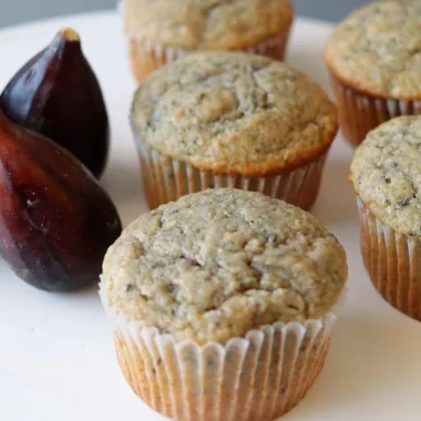 several fig muffins on a white plate with fresh figs.
