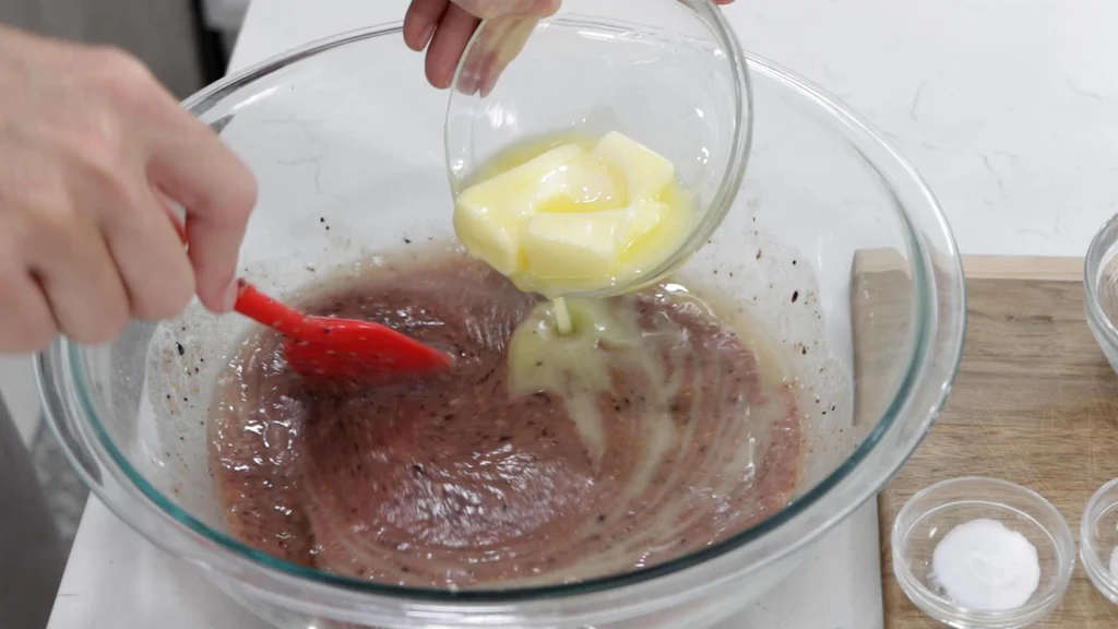 Pouring melted butter into a bowl with fig muffin batter. Pouring melted butter into a bowl with fig muffin batter.
