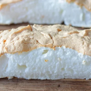 Cloud bread sliced in half on top of a wooden cutting board.