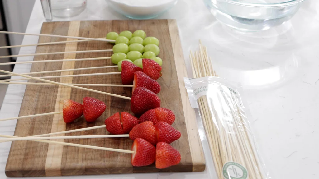Strawberries and grapes stuck to bamboo skewers.