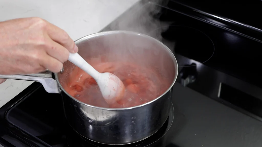 Stirring a pot filled with strawberries, honey, and lemon juice. Stirring a pot filled with strawberries, honey, and lemon juice.