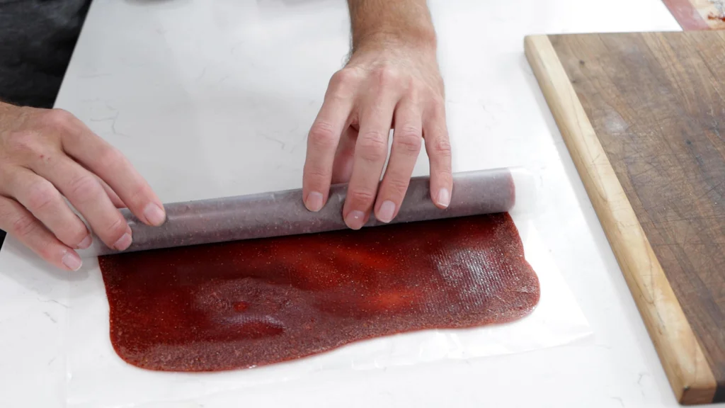 Rolling up the strawberry fruit leather in wax paper. Rolling up the strawberry fruit leather in wax paper.