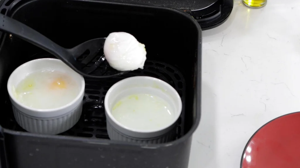 Finished poached eggs in ramekins in an air fryer basket. Finished poached eggs in ramekins in an air fryer basket.