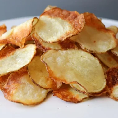 Pile of air fryer potato chips on a white plate.