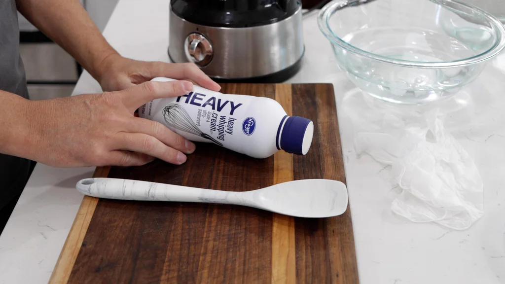 Hands holding a container of heavy whipping cream. Hands holding a container of heavy whipping cream.