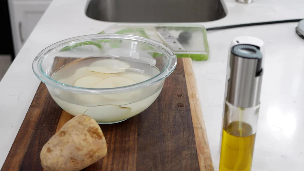 Slices of potato in a bowl with cold water. Slices of potato in a bowl with cold water.
