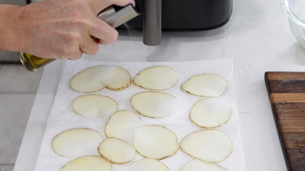 Spraying slices of potato with olive oil. Spraying slices of potato with olive oil.