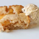 A plate with a slice of apple cobbler and a scoop of ice cream on it.