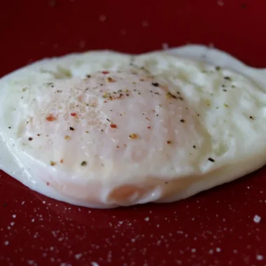 Over easy egg on a red plate.