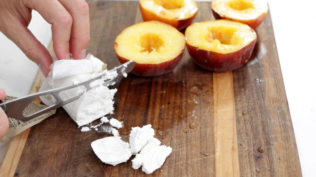 Hand slicing goat cheese with a cheese knife. Hand slicing goat cheese with a cheese knife.