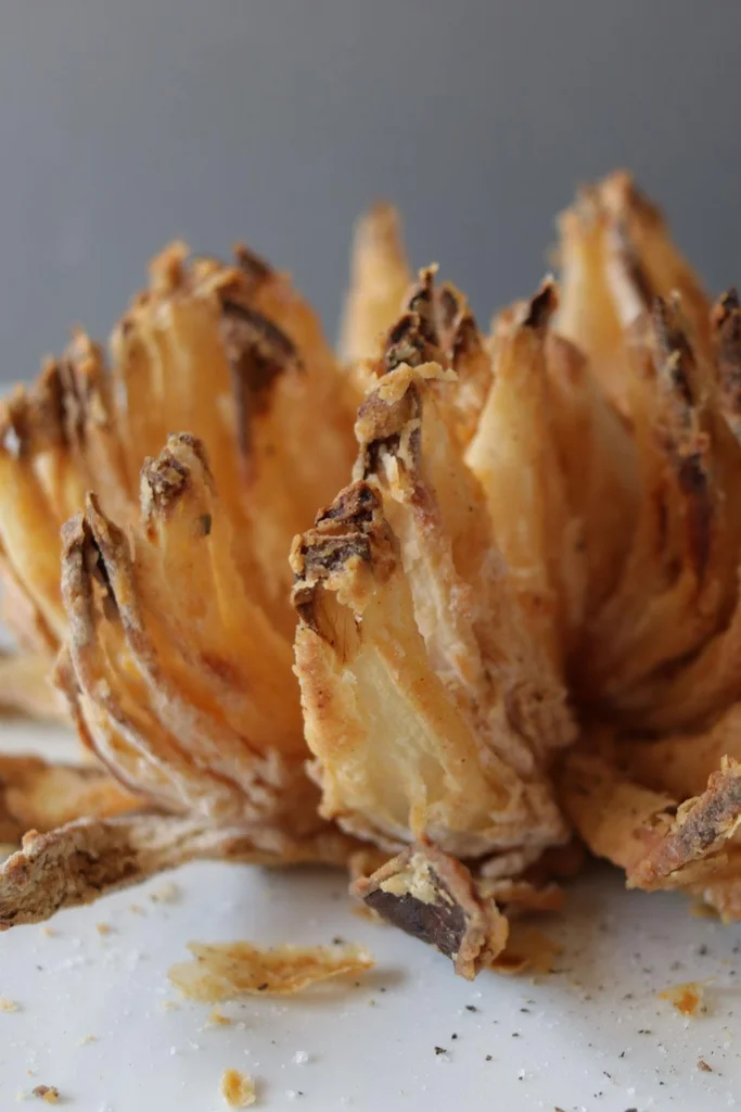 Air fryer blooming onion on a white plate. Air fryer blooming onion on a white plate.