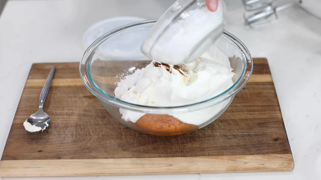 Several ingredients in a large mixing bowl including whipped topping, powdered sugar, pumpkin puree, etc. Several ingredients in a large mixing bowl including whipped topping, powdered sugar, pumpkin puree, etc.