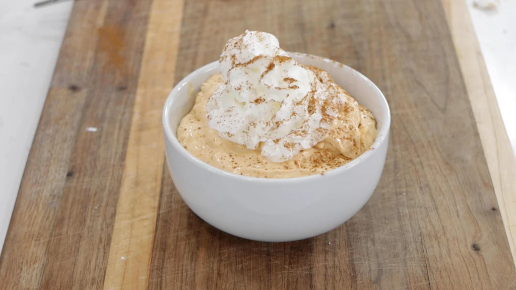 Bowl with no-bake pumpkin pie filling and whipped cream. Bowl with no-bake pumpkin pie filling and whipped cream.