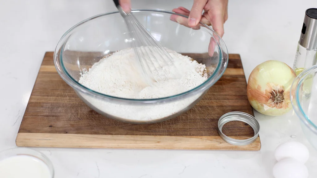 Hand whisking flour and other ingredients in a large bowl. Hand whisking flour and other ingredients in a large bowl.