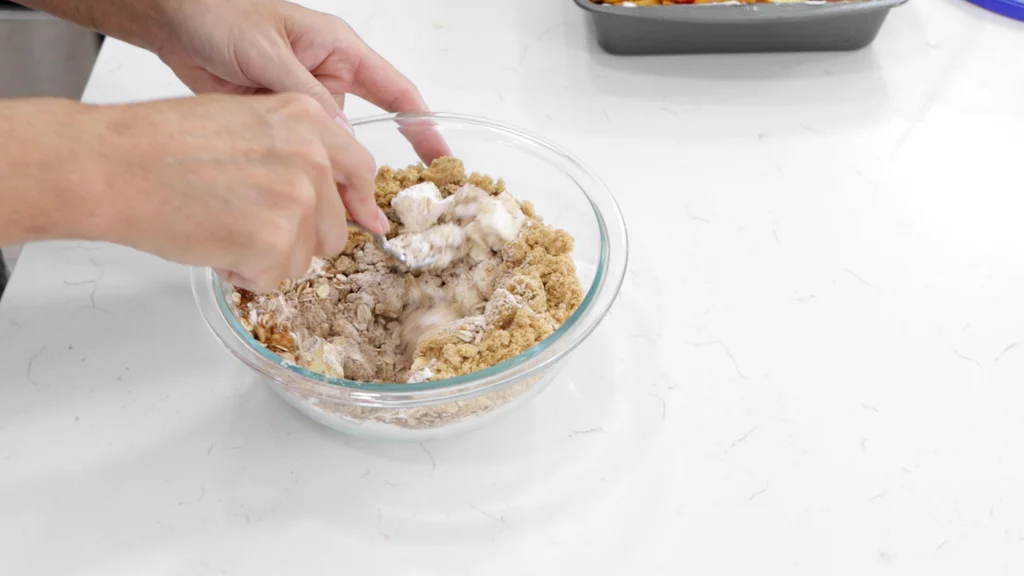 Hand mixing butter with sugar, flour, and oats. Hand mixing butter with sugar, flour, and oats.