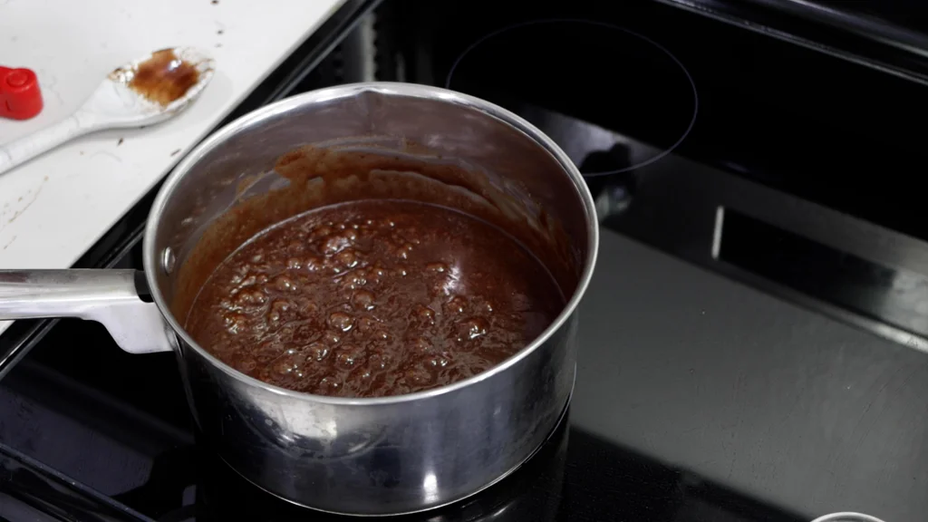 Stainless steel pot on a burner with boiling fudge in it. Stainless steel pot on a burner with boiling fudge in it.