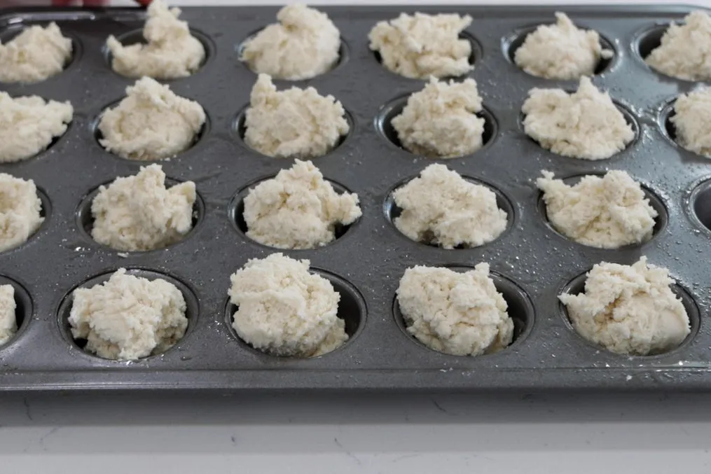 Mini muffin pan filled with biscuit dough ready to go in the oven. Mini muffin pan filled with biscuit dough ready to go in the oven.