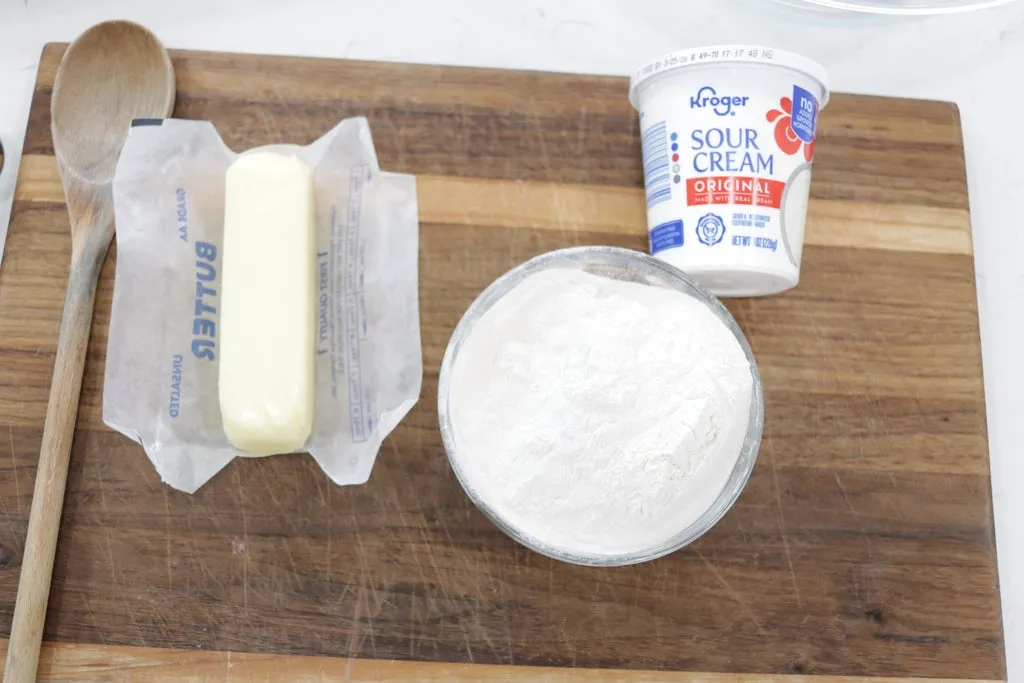 Butter, sour cream, and self-rising flour on a wooden cutting board. Butter, sour cream, and self-rising flour on a wooden cutting board.