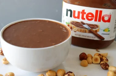 A white bowl filled with homemade Nutella next to a container of actual Nutella