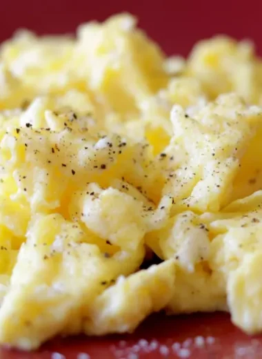 A red plate with a pile of perfectly cooked scrambled eggs.